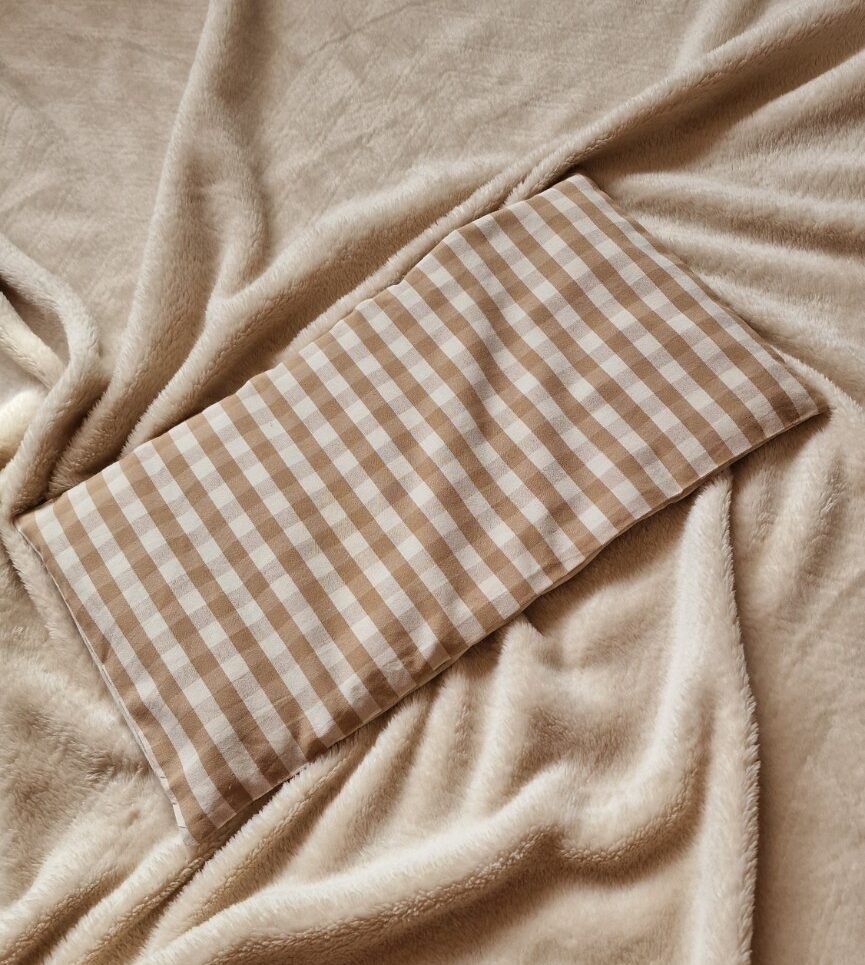 Grande bouillotte sèche Vichy brun beige posée sur une couverture beige
